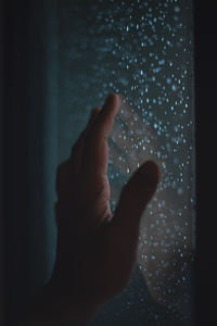 Close-up of human hand on wet window