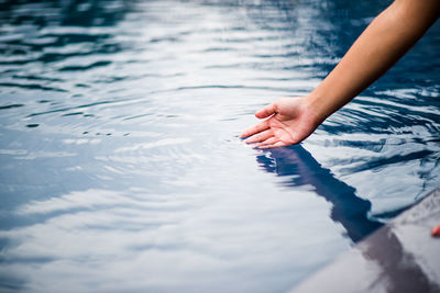 Cropped hand touching water