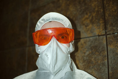 Portrait of person wearing mask against wall