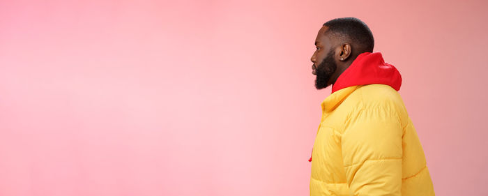 Rear view of woman standing against yellow background