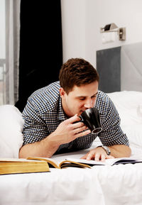 Young man sitting on bed at home