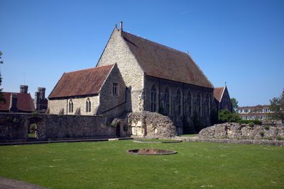 Lawn by building against clear blue sky