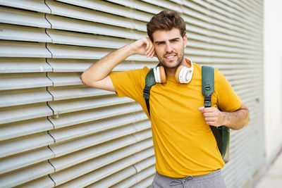 Portrait of young man standing by wall outdoors