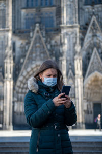 Full length of woman using mobile phone in city