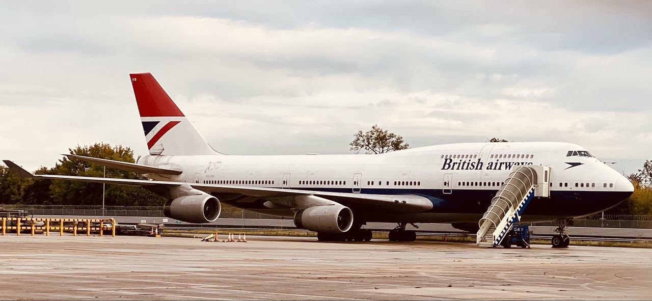 VIEW OF AIRPLANE ON AIRPORT RUNWAY AGAINST SKY