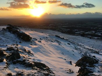 Scenic view of snow covered land against sky during sunset