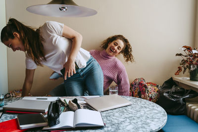 Cheerful young women exchanging seats at home