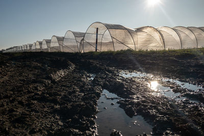 Low-angle view of foil greenhouses against sky