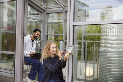 Young woman using mobile phone while standing in office