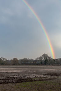 Scenic view of rainbow over field against sky