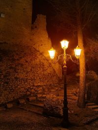 Illuminated street light against wall at night