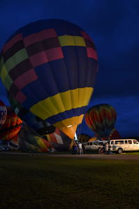 Multi colored hot air balloons on field against sky