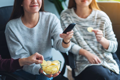 Friends eating potato chips while watching tv together