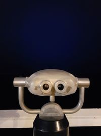 Close-up of coin-operated binoculars against black background