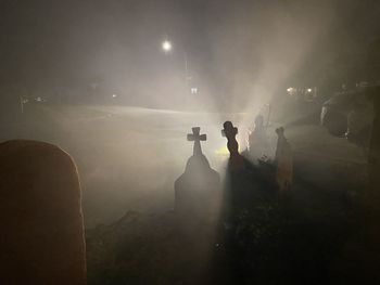 Silhouette people standing by illuminated street light at night