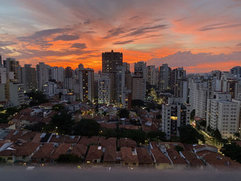 Illuminated buildings in city against sky during sunset