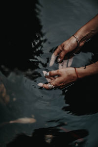 Female hands inside the dark water of the pond