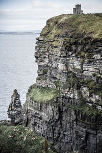 Rock formation by sea against sky