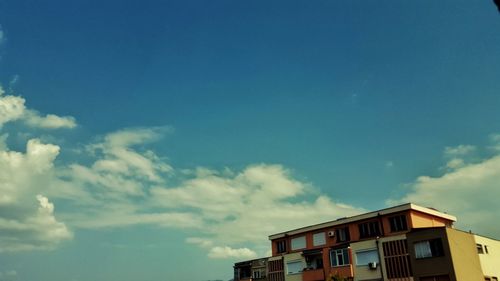 Low angle view of buildings against blue sky and clouds