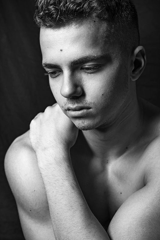 one person, portrait, young adult, headshot, indoors, shirtless, young men, real people, black background, looking, close-up, lifestyles, front view, contemplation, looking away, focus on foreground, handsome, beautiful people, teenager