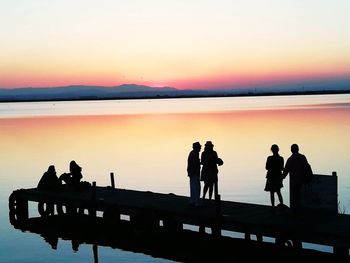 People standing on pier at sunset