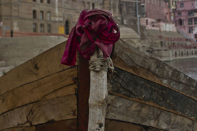 Close-up of rose tied on wood against building in city