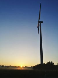 Windmill on field against clear sky during sunset