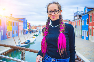 Portrait of young woman standing against railing