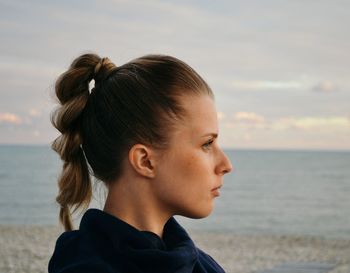 Side view of woman with braided hair at beach against sky