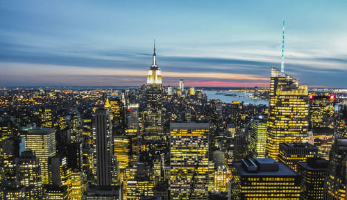 Aerial view of city lit up against cloudy sky