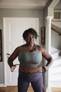 Mature woman stretching resistance band while exercising at home