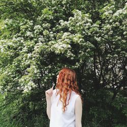 Midsection of woman standing by tree against plants