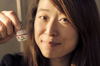 Close-up portrait of smiling young woman holding cat key ring