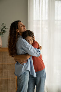 Side view of young woman looking away while standing at home