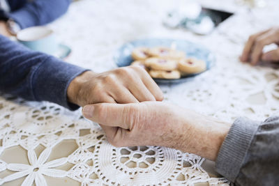 Cropped image of caretaker consoling man at dining table