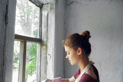 Side view of young woman looking through window