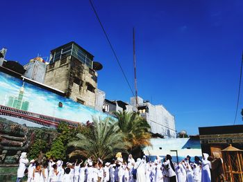 Group of people in front of building against blue sky