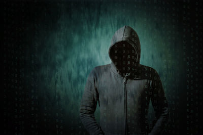 Digital composite image of hacker with numbers against green background