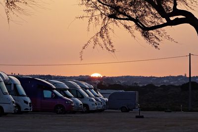 Cars on road against sky at sunset