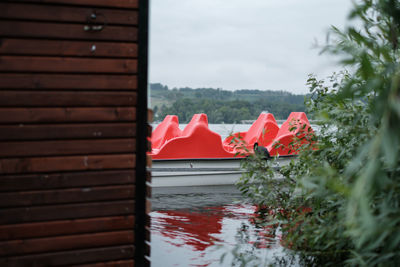 Red boats by lake against sky