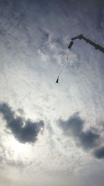 Low angle view of bird flying against cloudy sky