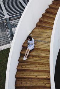 High angle view of woman playing with cat while sitting on staircase