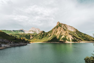 Scenic view of lake by mountains against sky