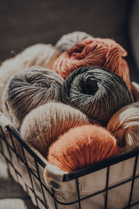 Close up of balls of earth coloured yarn inside a basket, sunlight from the window on it.