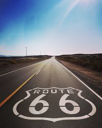 Route 66 written on road against blue sky