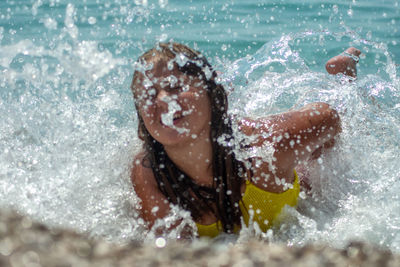 Waves splashing on girl lying in sea