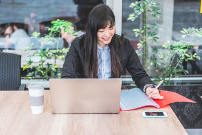 Woman using mobile phone while sitting on table