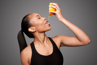 Close-up of young woman holding ice cream against gray background