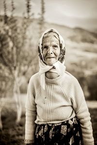 Portrait of senior woman wearing headscarf while standing against mountain
