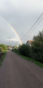 Rainbow over road against sky